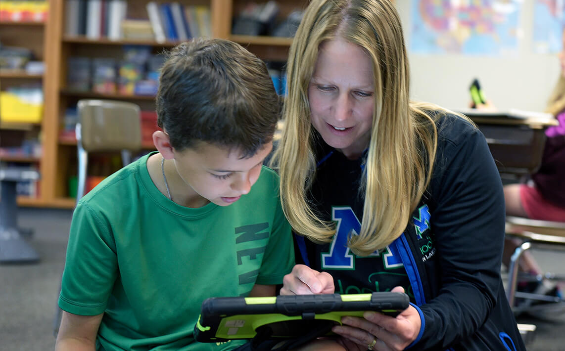 Teacher with young student looking at an ipad