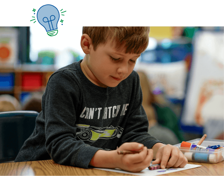 Preschool boy coloring in class