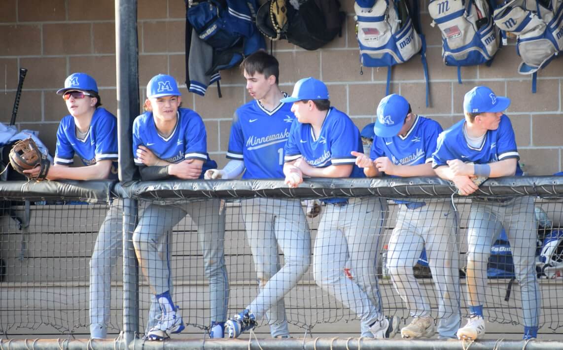 Team of baseball players in blue uniforms in the dugout.